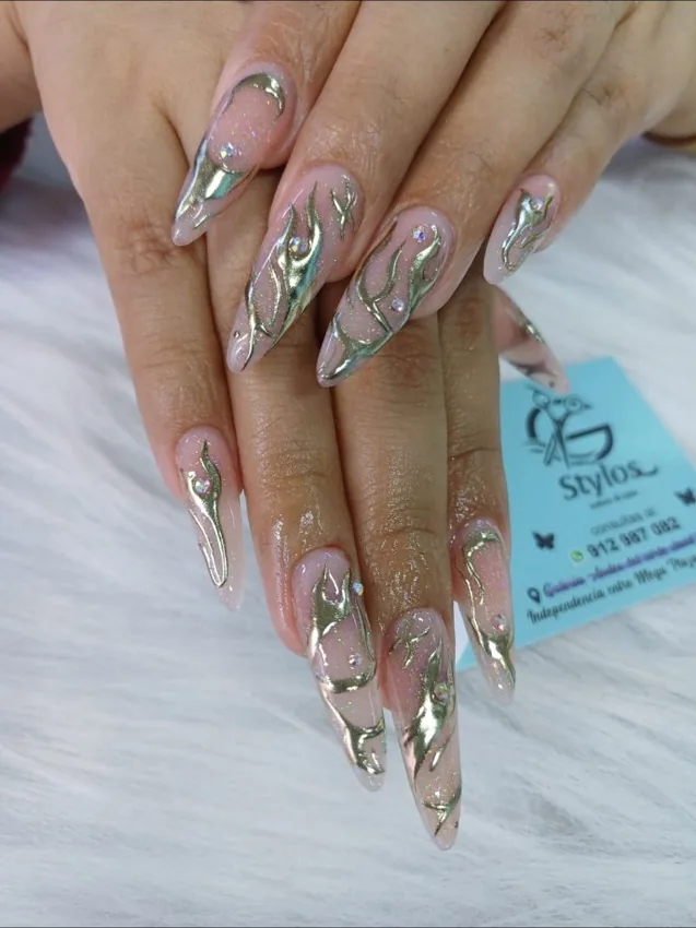 Uñas alargadas con adornos metálicos dorados